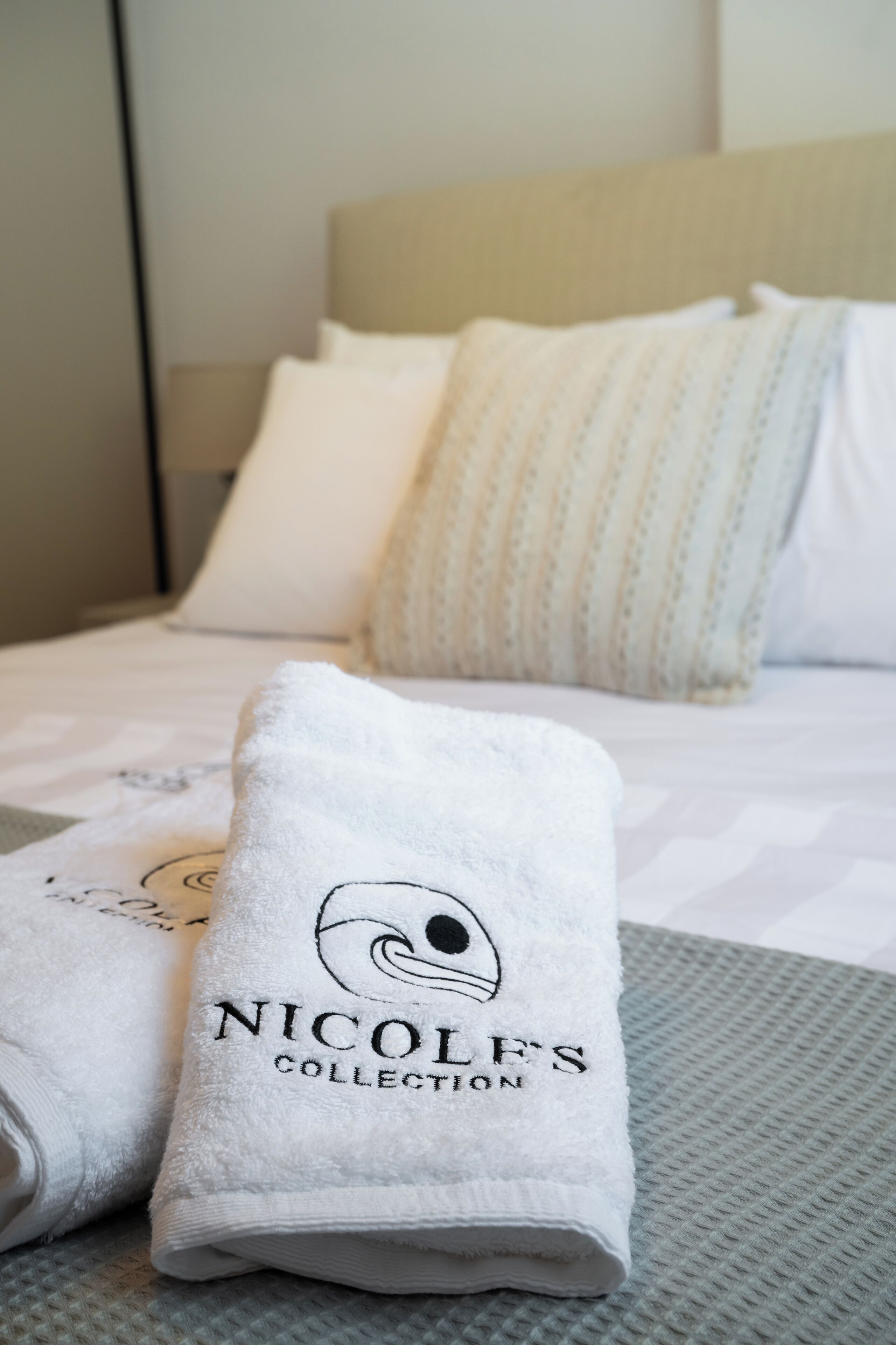 A neatly made bed with white bedding and a pillow with a striped pattern.