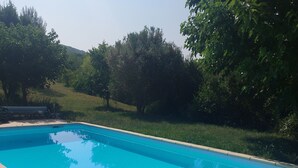 A rectangular swimming pool with a tiled edge, surrounded by a grassy area and trees. - Vacation cottage with heated pool in the heart of the Ibie Valley. (Saint-Maurice-d'Ibie)