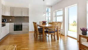 A modern kitchen with white cabinets, a built-in oven, and a dining area with a wooden table and chairs. - Stunning view, ski-in/ski-out, 3 bedrooms – Valdres (Aurdal)