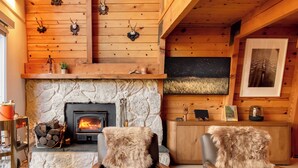 Un acogedor interior de cabaña con chimenea de piedra, paredes de madera y decoración rústica.