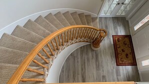 A spiral staircase with wooden balusters and a beige carpeted wall. - The Liberty House (Elegant, Stylish, Spacious) (Charlottetown)