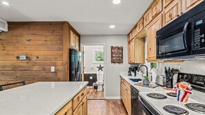 Une cuisine moderne avec des meubles en bois, un grand îlot central, un micro-ondes noir et une cuisinière.