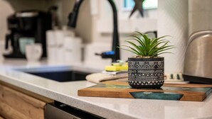 A kitchen counter with a coffee maker, a sink, and a potted plant on a wooden board. - NEW Listing 🔥 Hot Tub • Mountain View • Fire Pit • EV Charger (Sevierville)