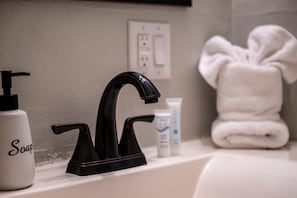 A bathroom sink with a black faucet, a soap dispenser, and a towel.