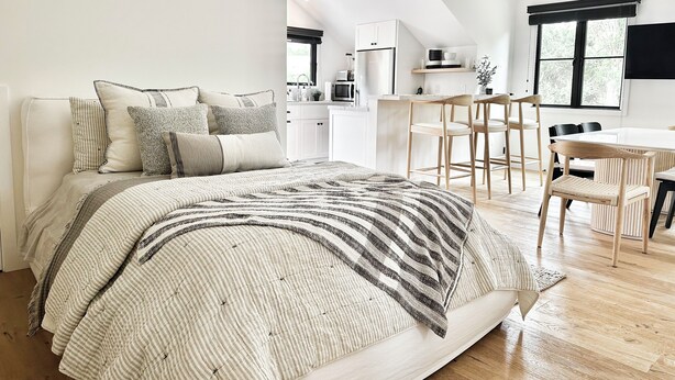 A modern bedroom with a large bed, a dining area with a table and chairs, and a kitchen in the background. - Newly built designer guesthouse nestled in Santa Barbara’s Sycamore Canyon. (Santa Barbara)
