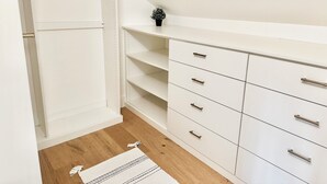 A walk-in closet with open shelves and drawers, a small plant on top, and a wooden floor. - Newly built designer guesthouse nestled in Santa Barbara’s Sycamore Canyon. (Santa Barbara)