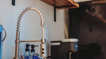 Une cuisine avec des étagères en bois, une machine à café et un évier.