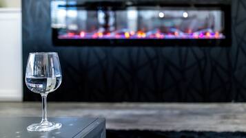 Un verre d’eau transparent posé sur une table, avec une cheminée moderne en arrière-plan.