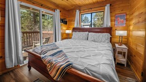 Une chambre dans une cabane en bois, avec un grand lit, deux tables de chevet et un ventilateur de plafond.