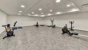 A gym with various exercise equipment, including an elliptical, stationary bike, and a rowing machine.