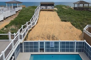 Ein Anwesen am Strand mit Schwimmbad, Holzterrasse und Zugang zum Strand.
