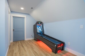 A room with a pinball machine, a door, and a light switch on the wall. - 5389- Heavenly Sunrise - Oceanfront Estate for 32 | Pool & Theater (Kill Devil Hills)