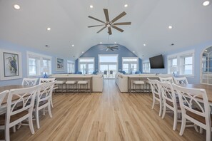A spacious kitchen with a central island, white chairs, and a ceiling fan. - 5389- Heavenly Sunrise - Oceanfront Estate for 32 | Pool & Theater (Kill Devil Hills)