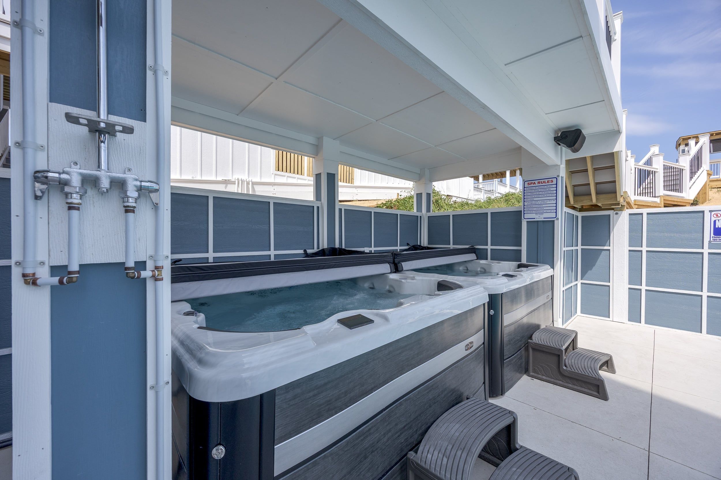 Un espace spa comprenant plusieurs bains à remous, un espace détente couvert et un panneau indiquant les règles à respecter dans le spa.