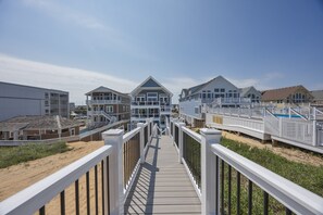A boardwalk leading to beachfront properties with balconies and a pool.