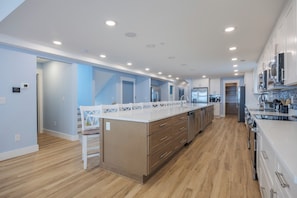 Una cocina moderna con una isla central, armarios de madera y electrodomésticos de acero inoxidable.