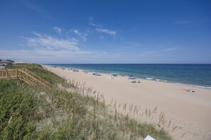 A beach with a wooden boardwalk leading to the shore, clear skies, and a calm sea. - 5389- Heavenly Sunrise - Oceanfront Estate for 32 | Pool & Theater (Kill Devil Hills)