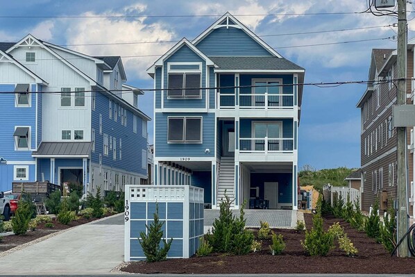 A multi-story residential building with a balcony, a garage, and a small garden area.