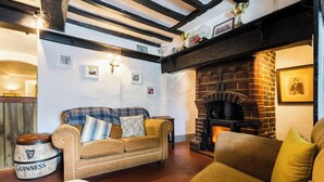 A cozy living room with a fireplace, a sofa, and a wooden barrel. - Hawk and Buckle Inn (Llannefydd)