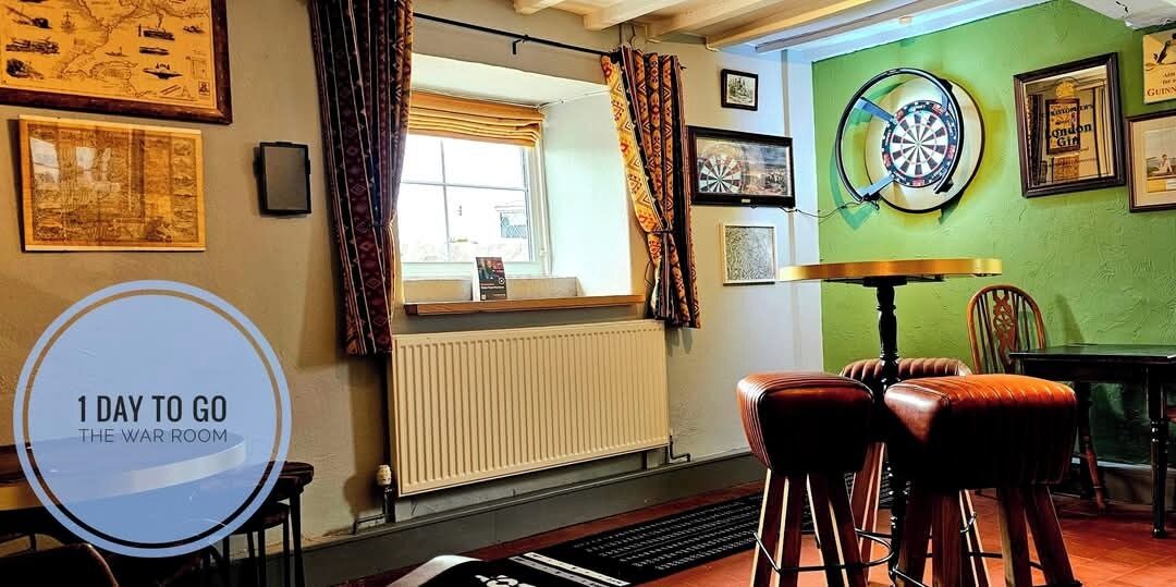 A room with a dartboard, a table, and a window with curtains.