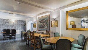 A dining area with a large wooden table and chairs, a patterned wallpaper wall, and a large mirror on the right. - Hawk and Buckle Inn (Llannefydd)