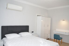 A bedroom with a bed, a wardrobe, a desk, and a chair.