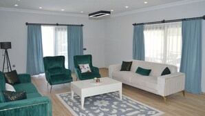 A modern living room with a white sofa, green armchairs, a white coffee table, and a patterned rug. - VILLA WITH LAKE AND FOREST VIEW IN DALYAN2 (Akcakavak)