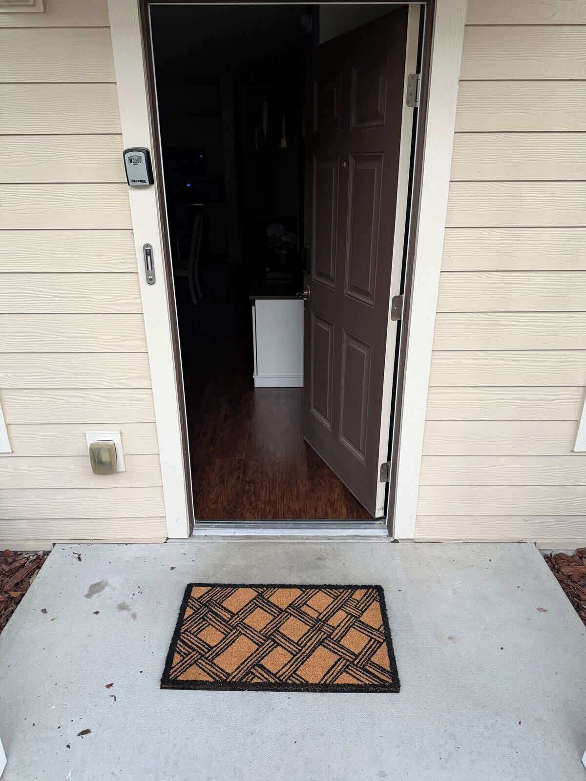 A house entrance with a door, a mailbox, and a doormat.
