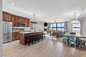 Una cucina moderna con mobili impiallacciati in legno, elettrodomestici in acciaio inox e un'isola centrale con sgabelli da bar.