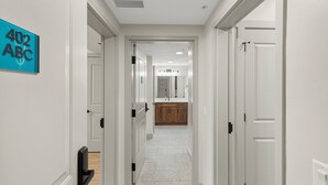 A hallway with white walls, a sign reading '402 ABC', and a view into a room with a sink and cabinets.