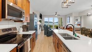 A modern kitchen with stainless steel appliances, wooden cabinets, and a large island with a sink.