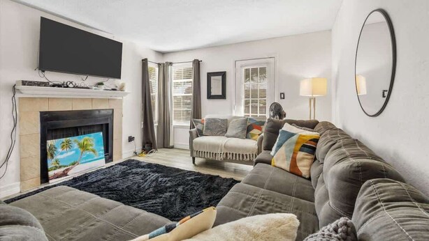 Una sala de estar con televisión de pantalla plana, chimenea, sofá y un espejo grande.