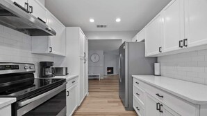 Een moderne keuken met witte kastjes, een rvs fornuis en een inbouwoven.
