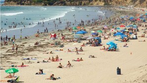 Ein überfüllter Strand mit Menschen, die sich sonnen und schwimmen.