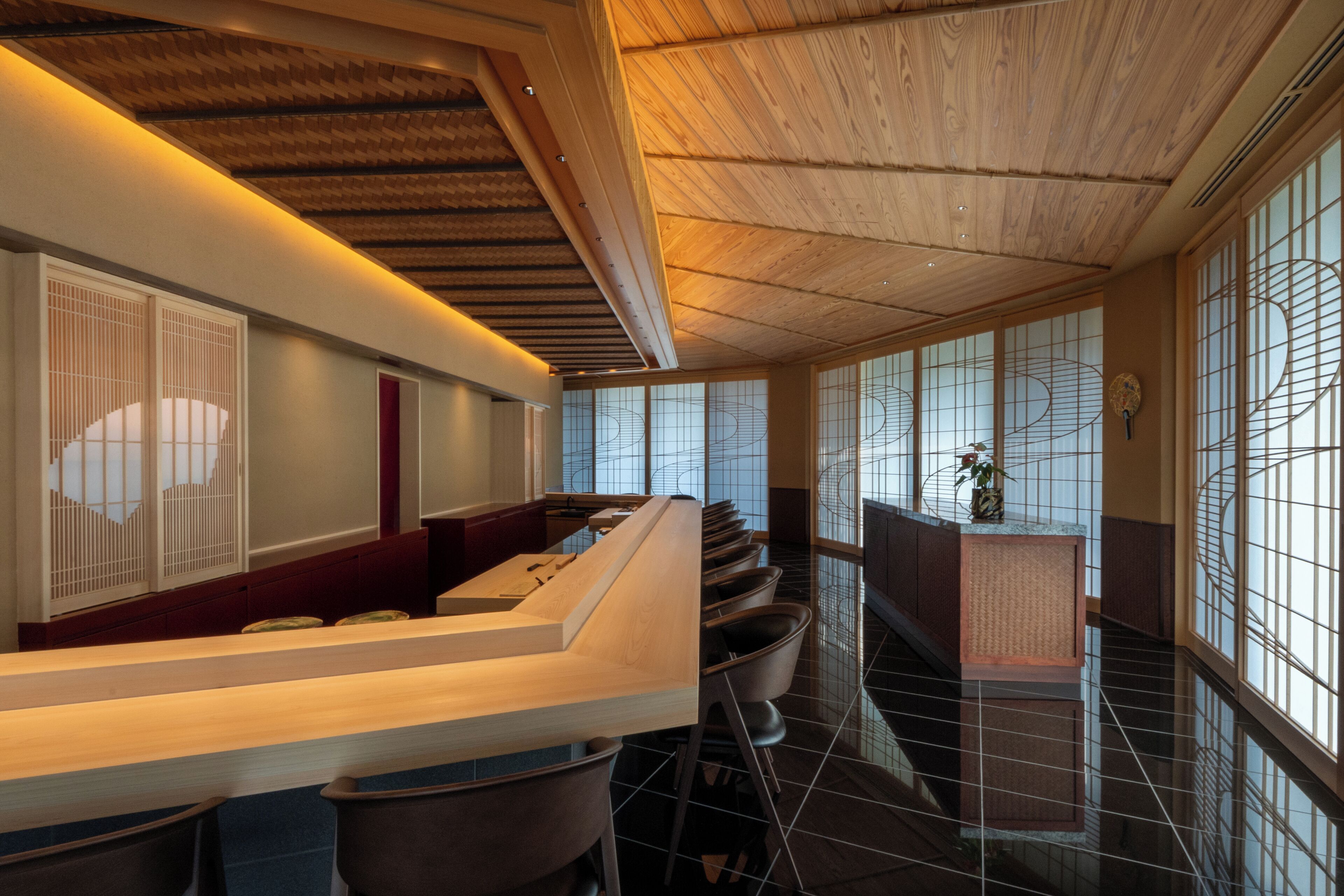 Un intérieur moderne avec un plafond en bois, un comptoir d’accueil et une vue dégagée grâce à de grandes fenêtres.