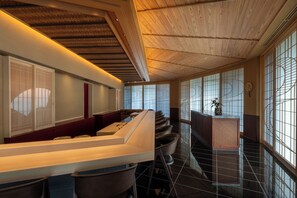 A modern interior with a wooden ceiling, a reception desk, and a view through large windows. - PGM Hotel Resort Okinawa (Onna)