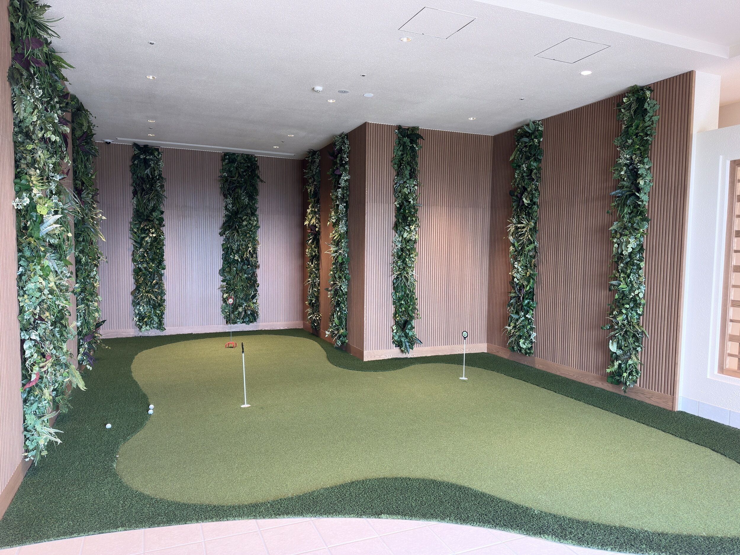 A room with artificial turf, vertical greenery, and wooden panel walls.