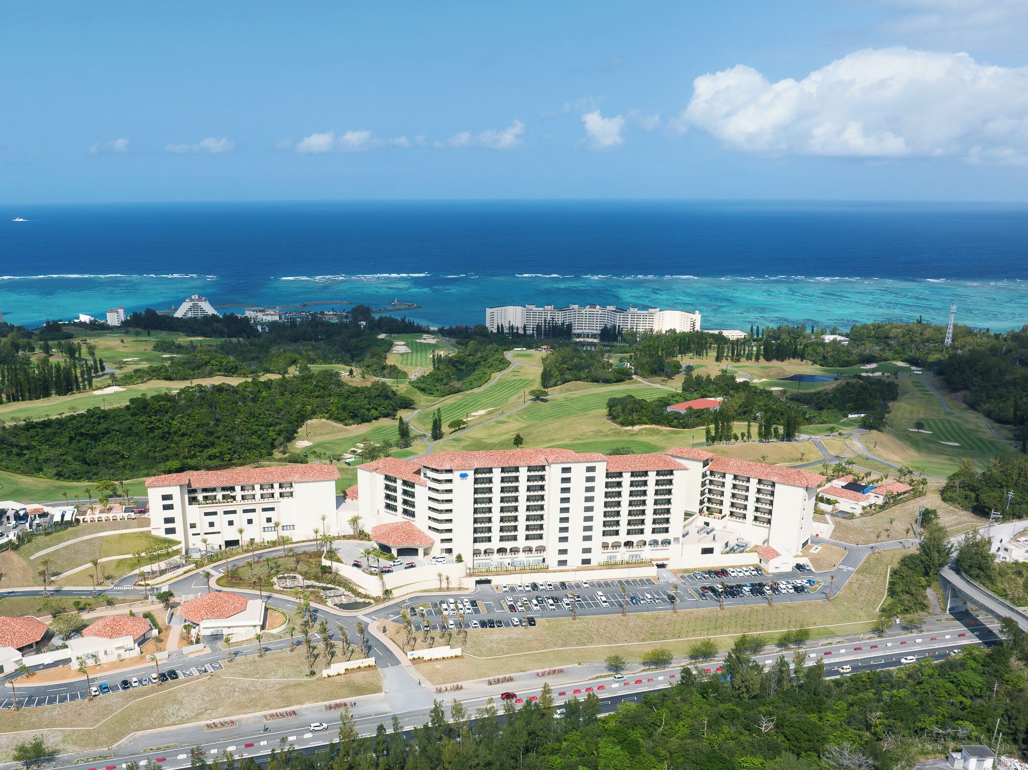 Ein Resort mit einem großen Gebäude, einem Parkplatz und Blick auf den Ozean.