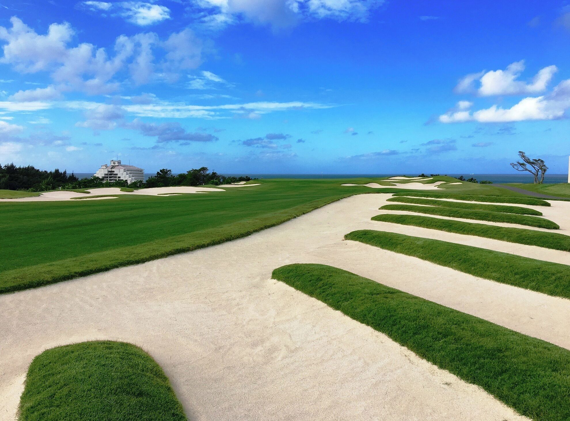 Un parcours de golf avec des bunkers de sable et un bâtiment en arrière-plan.