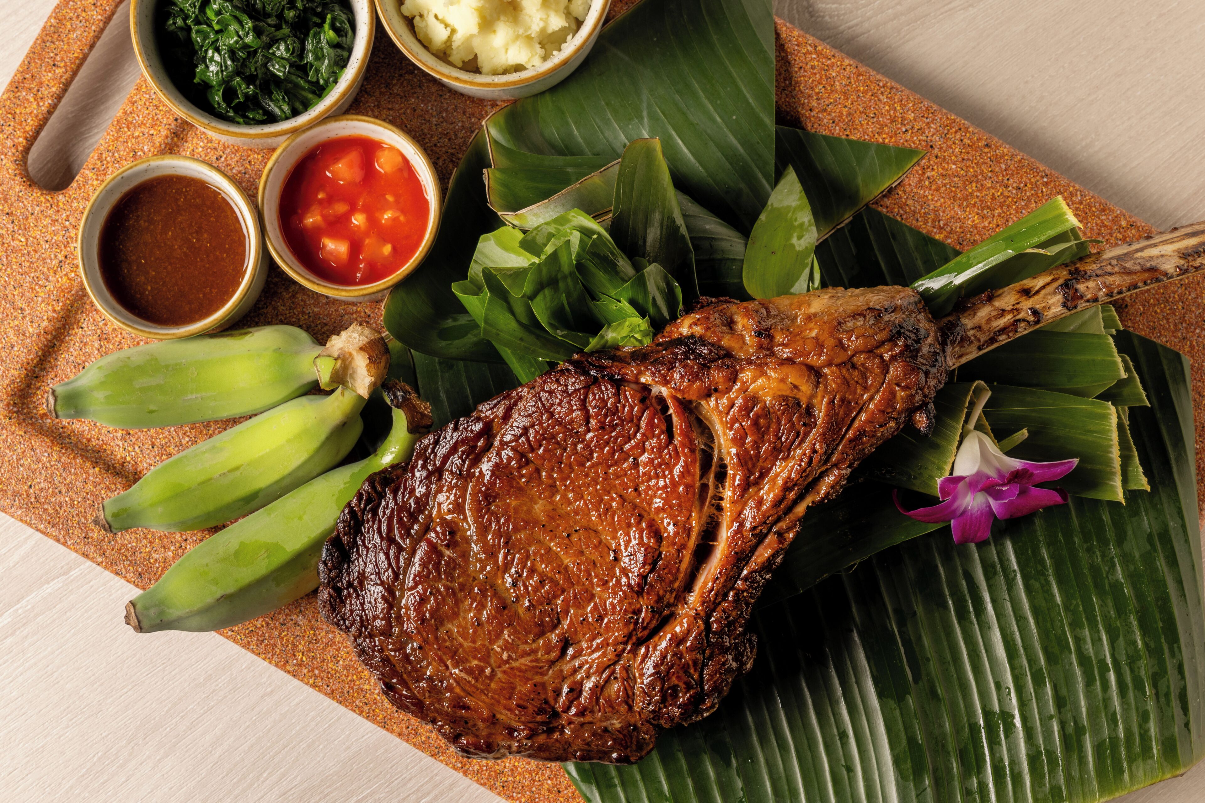 A roasted lamb on banana leaves with side dishes.