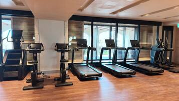 Un gimnasio con cintas de correr, elípticas y suelo de madera.