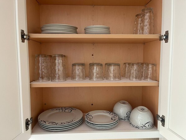 A cabinet with shelves holding plates, glass jars, and a decorative bowl. - VENICE OASIS (Venice)