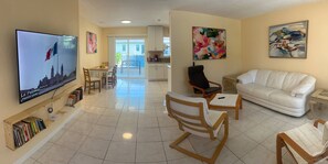 A spacious living room with a flat-screen TV, a white sofa, wooden chairs, and a dining area with a table and chairs. - VENICE OASIS (Venice)