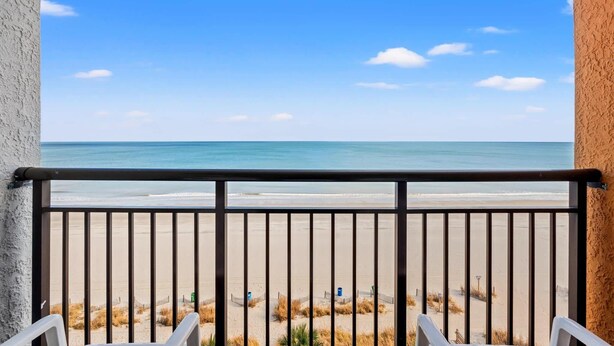 Un balcon avec vue sur une plage et l’océan.