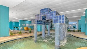 Un espace piscine avec une structure recouverte de carreaux bleus immergée dans l’eau, une eau claire et un plafond carrelé.