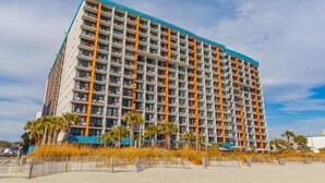 Un hôtel à plusieurs étages, doté d’une série de balcons disposés en réseau, d’un toit plat et situé en bord de mer.
