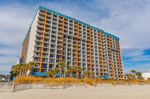 A multi-story hotel with a grid of balconies, a flat roof, and a beachside location.