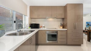 Una cocina moderna con un lavamanos de acero inoxidable, horno empotrado y armarios de madera.