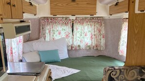 A compact RV interior with a bed, a kitchenette, and a seating area. - Glamping Casita RV on the Backbone with Stunning Views All Around (Fischer)