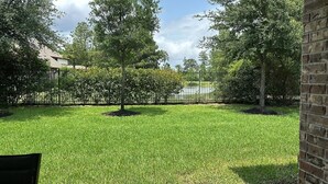 A well-maintained grassy yard with trees and a brick wall. - Woodlands House. 8 People, Restaurants, Movie Theater, HEB, Parks and Walkways. (Tomball)